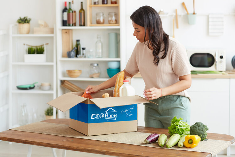 Customer in kitchen opening meal-kit delivery box