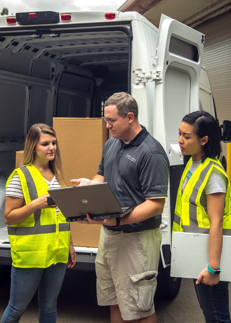 Manager holding laptop speaking to two employees